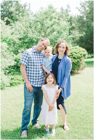 Spring family portrait with casual checkered shirt and blue cardigan against blooming trees.