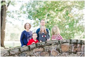 Group poses together on stone wall surrounded by trees.