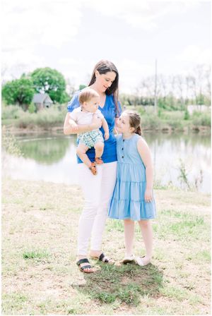 Three people stand together by pond on sunny spring day.