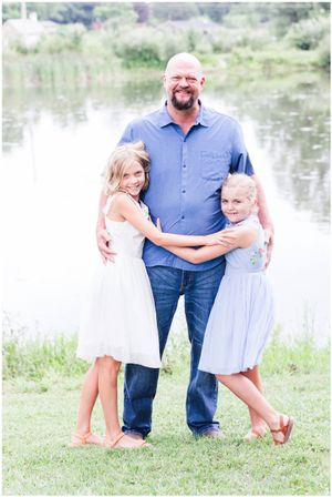 A heartwarming portrait of three people hugging by a peaceful lake.