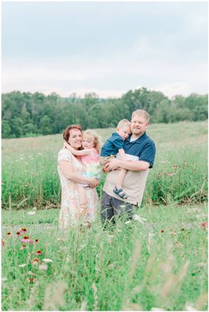 A family embraces while standing in a wildflower meadow on a sunny afternoon.
