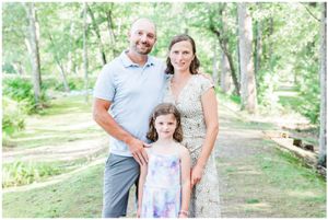Family of three poses together on a nature trail in summer attire.