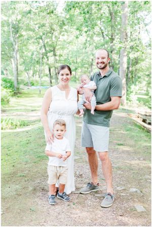Family of four poses together on a wooded path during summer.