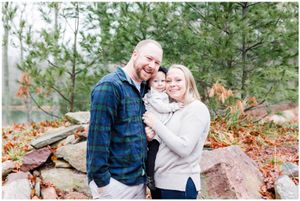 Couple embracing outdoors among pine trees and autumn foliage.