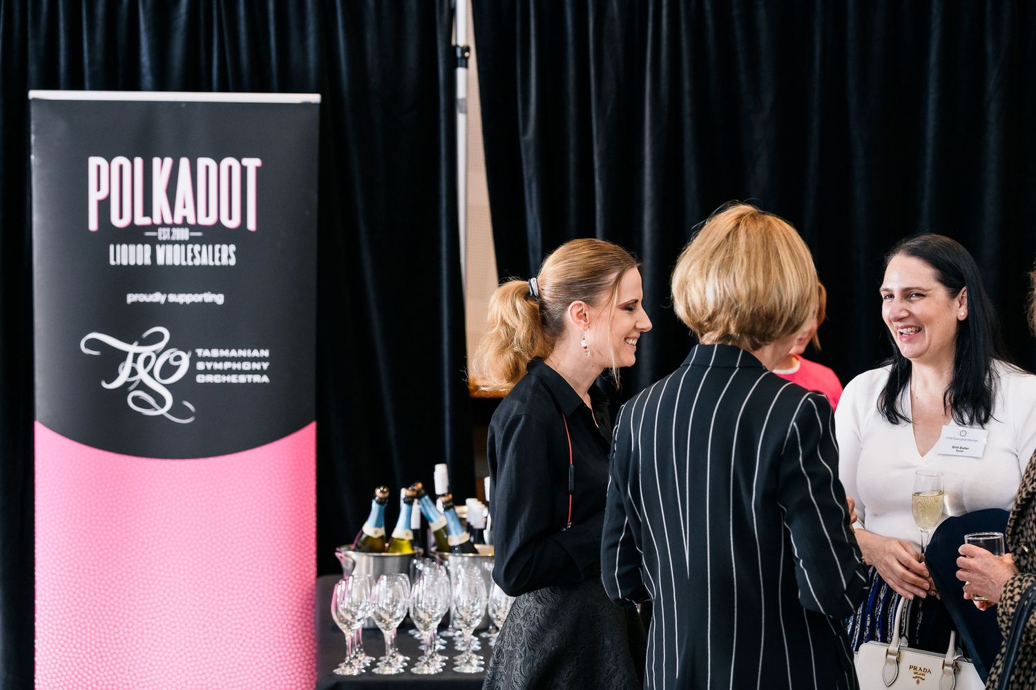 A social gathering at a Polkadot wine event with glasses displayed on a table.