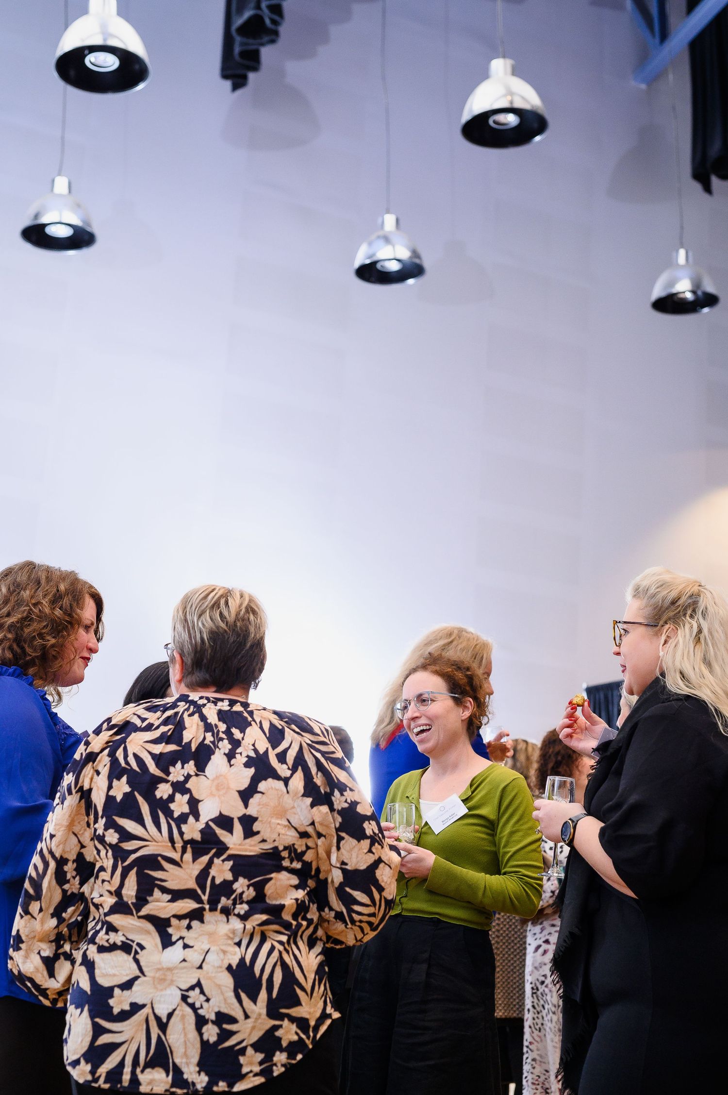 Group socializing under industrial pendant lights at an indoor networking event.