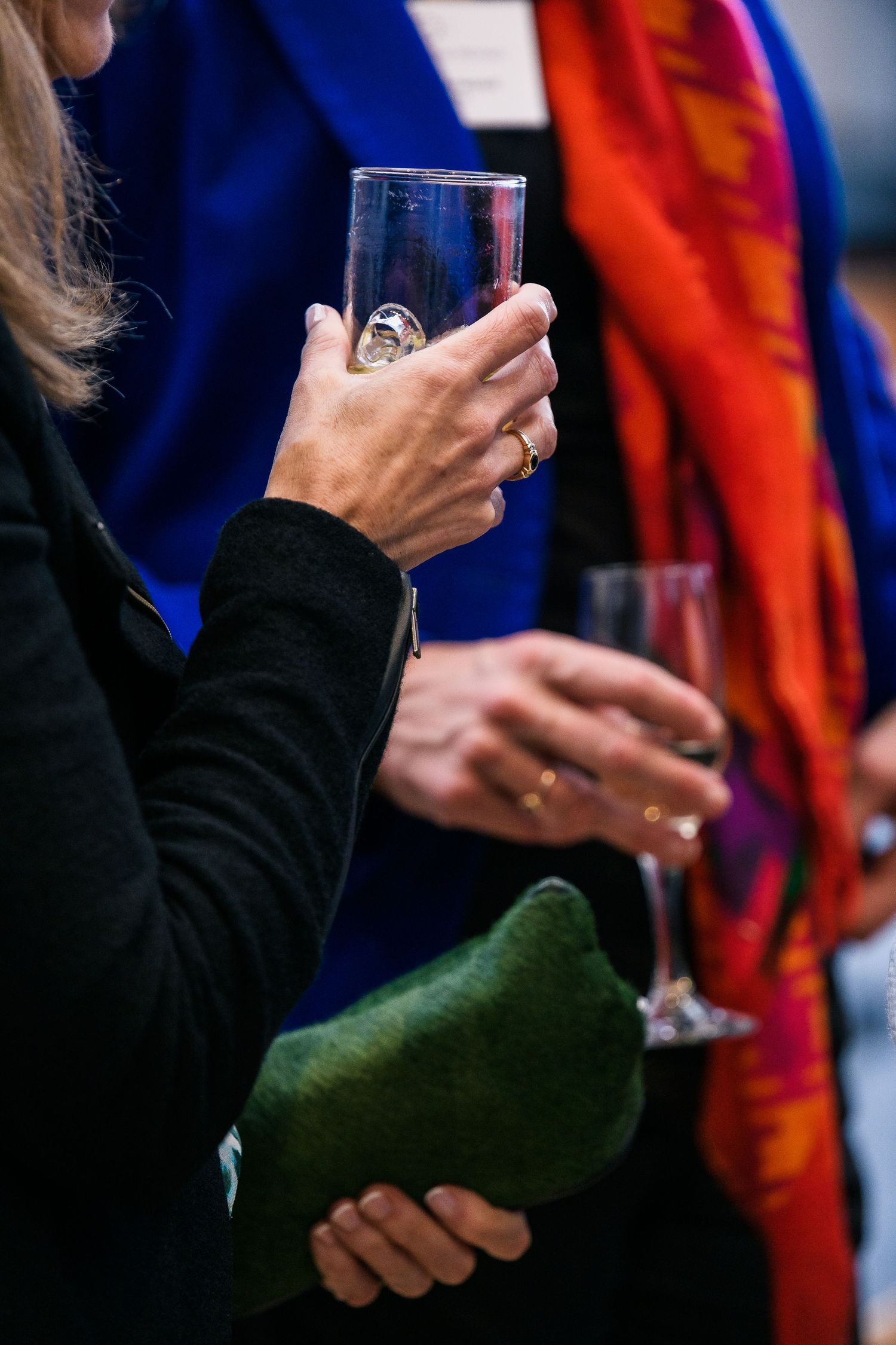 Close-up of hands holding wine glasses at a formal gathering.