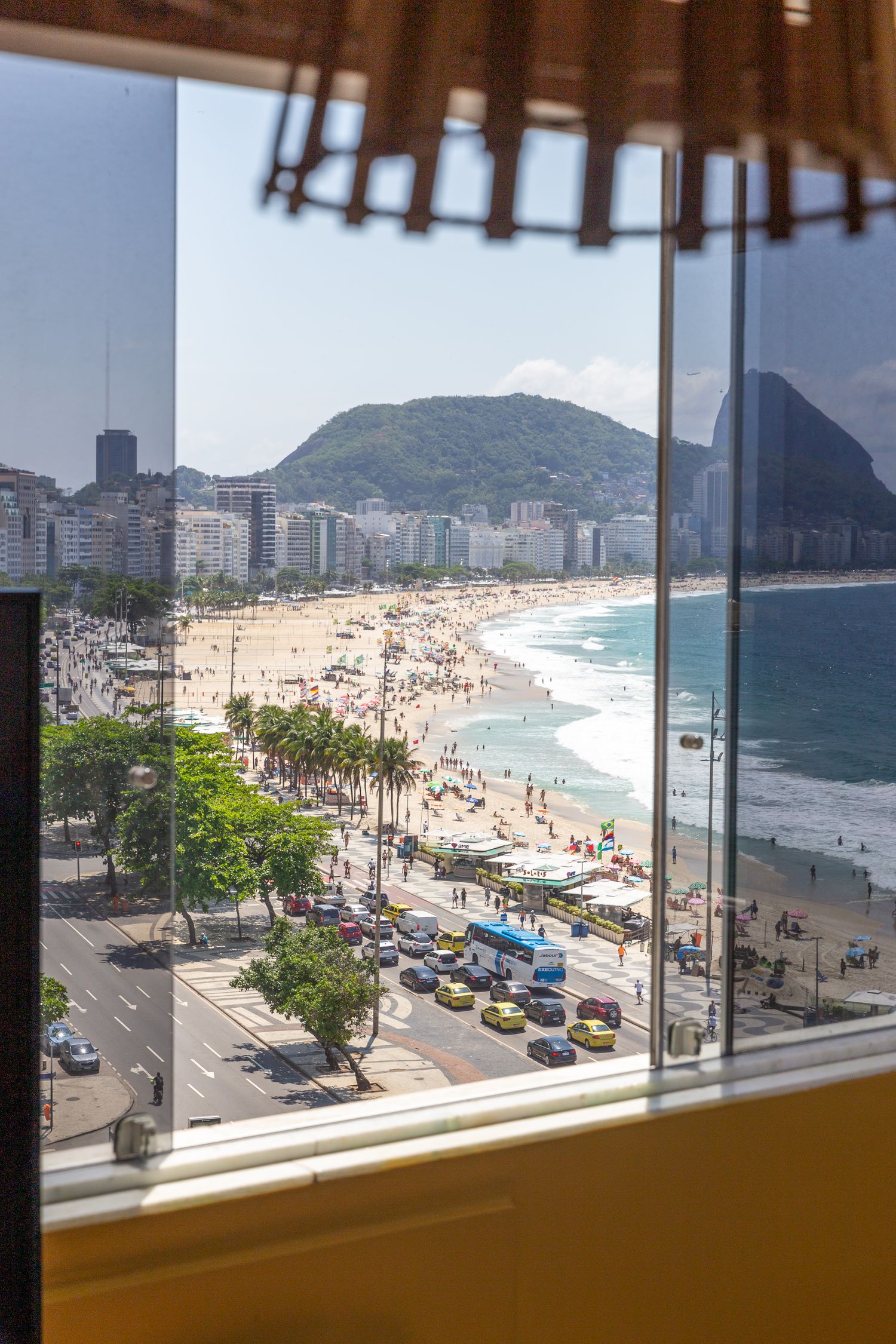Aerial view of Copacabana Beach showing busy beachfront boulevard and Sugarloaf Mountain.