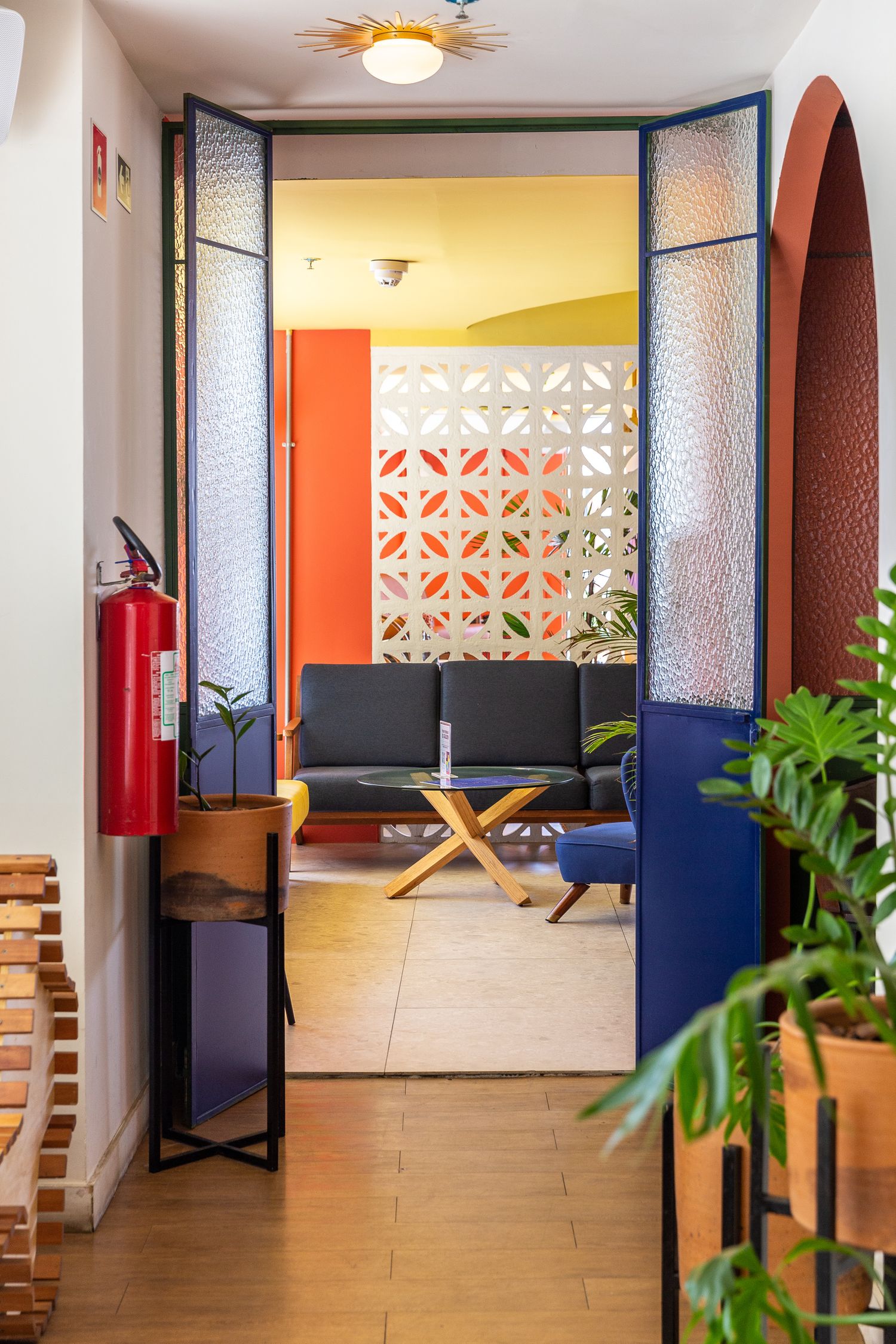 Modern lounge area with geometric wall divider and blue doors leading to seating space.
