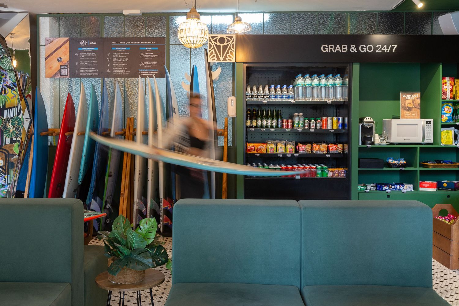 Surf shop interior with colorful surfboards displayed against teal walls and retail counter area.