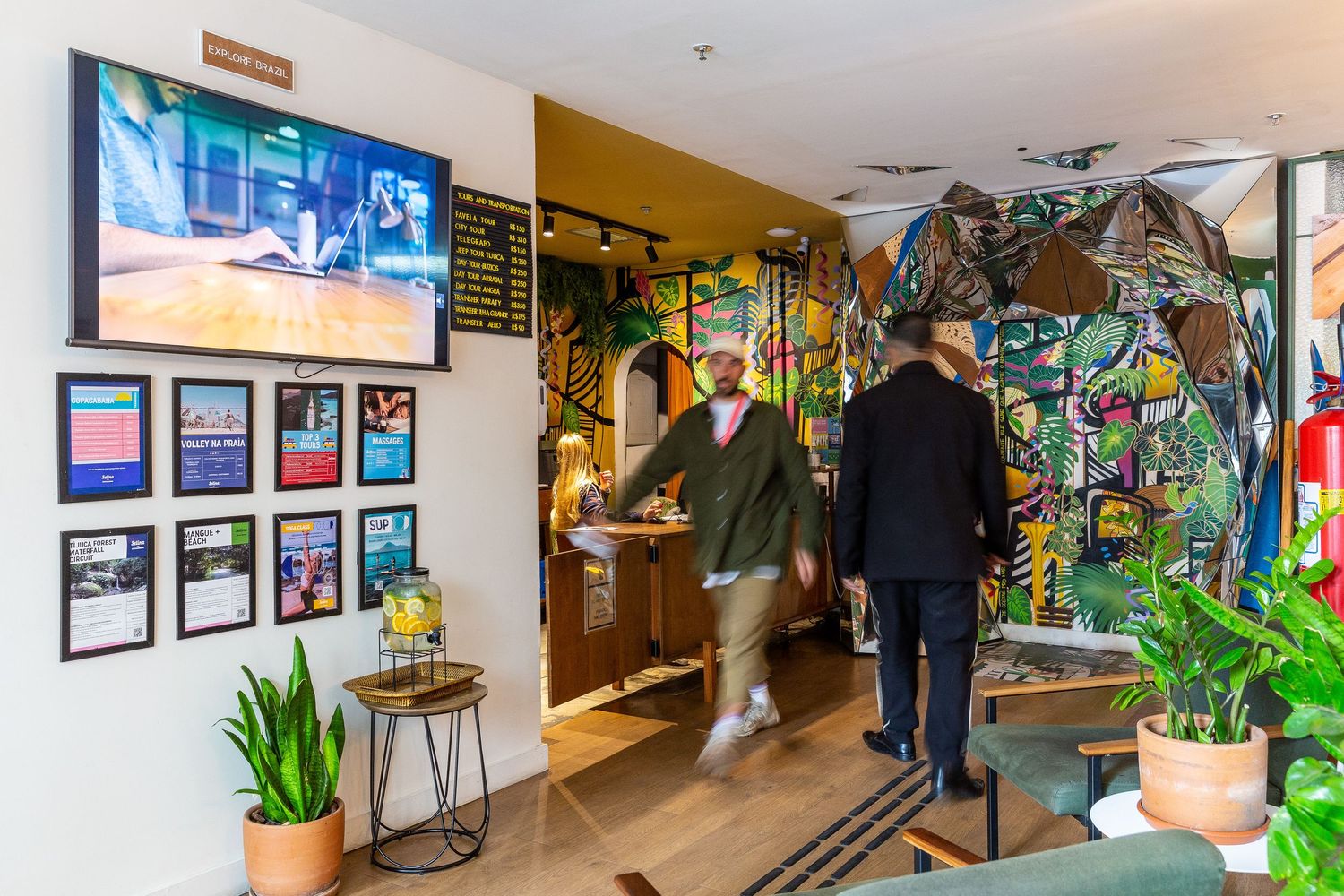 Modern cafe entrance with colorful wall mural and indoor plants near reception area.