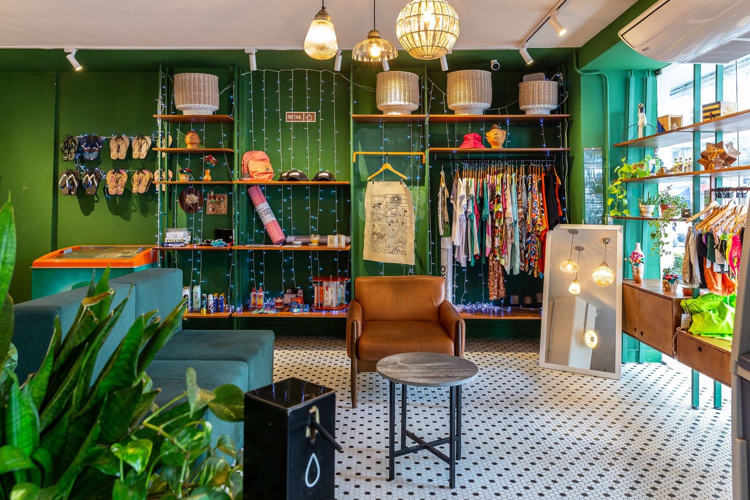 Boutique retail space with green walls, clothing racks, and vintage-style pendant lighting.