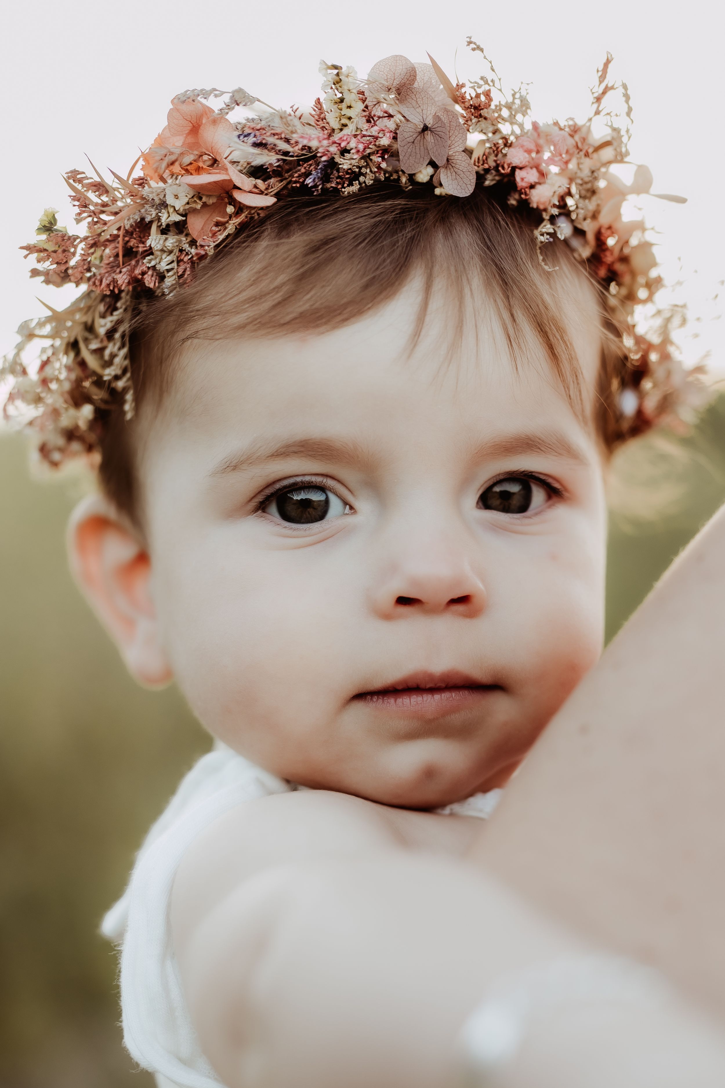 Close-up of baby wearing delicate floral crown with soft natural lighting.