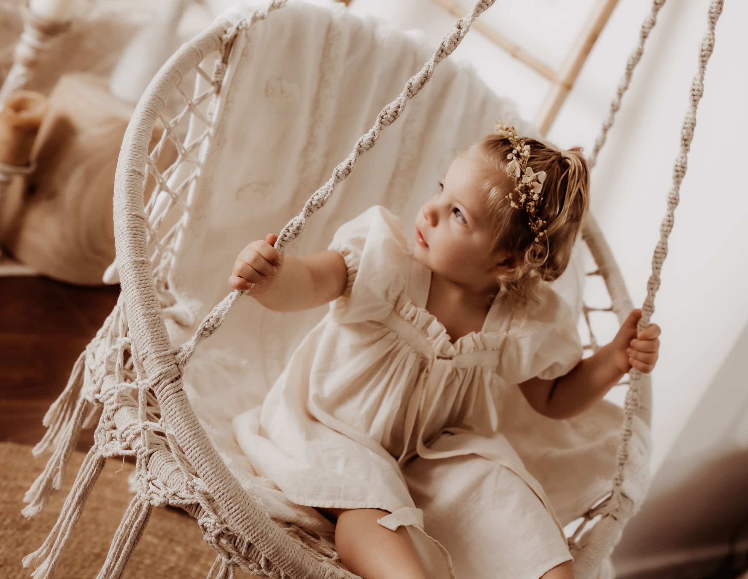 Dreamy portrait of babies in white lace dresses with soft window lighting.