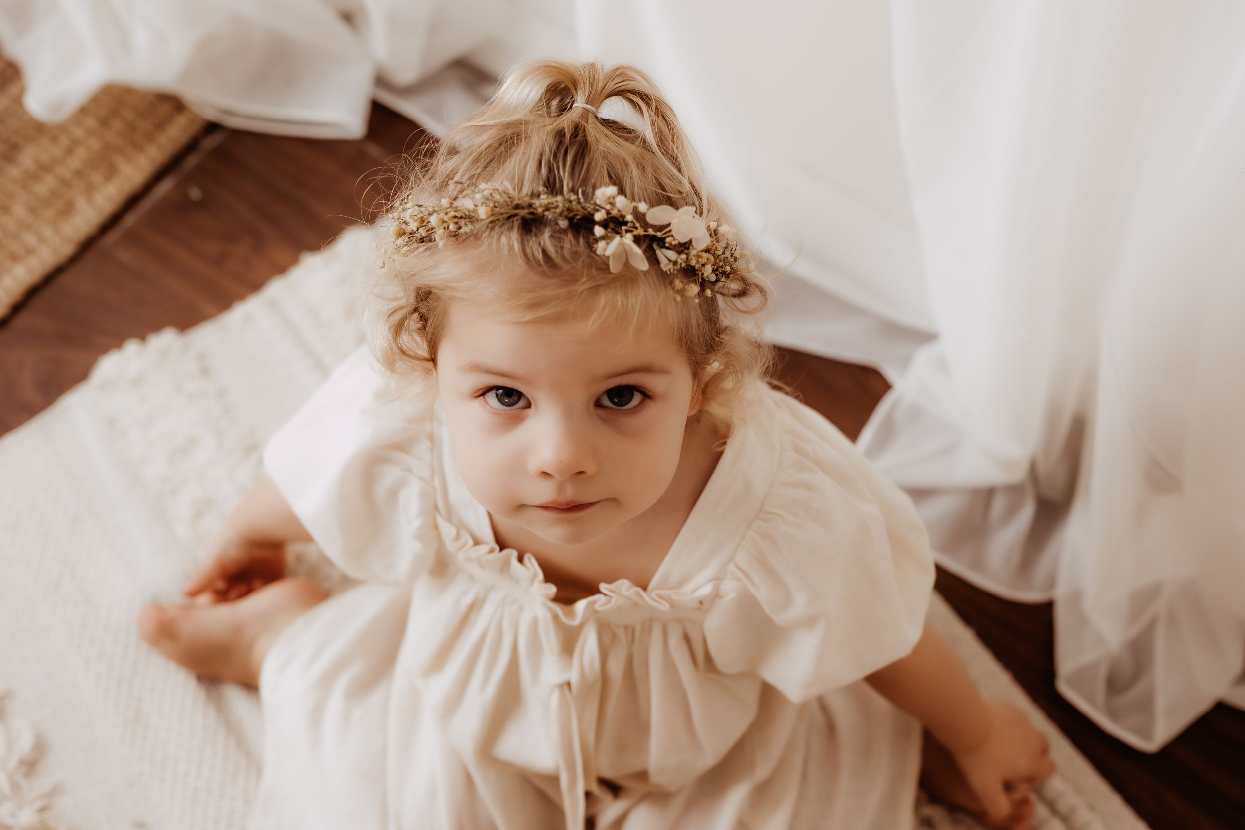 Child in vintage-inspired white dress with delicate details and natural lighting.