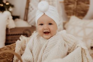 Baby wearing white knit sweater and bow during winter photoshoot.