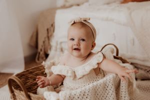 Smiling baby in vintage-style lace dress during holiday portrait session.