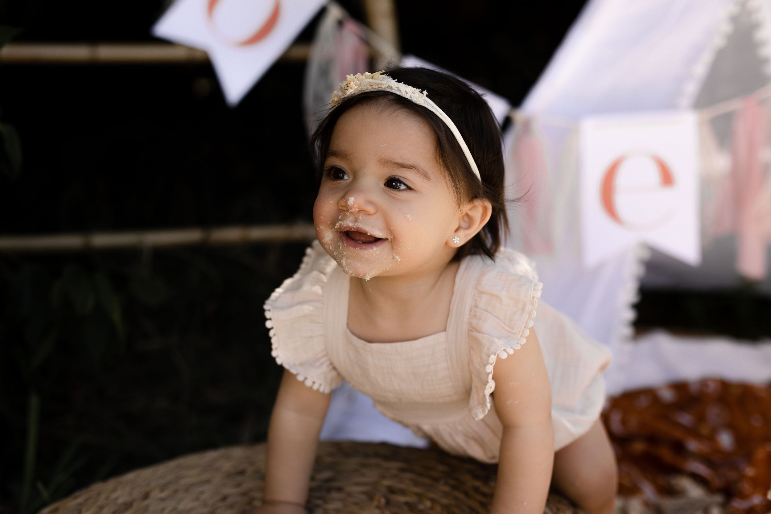 Sweet candid moment of baby wearing white dress and headband during photo session.