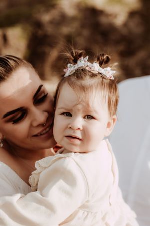 Mother and baby sharing intimate moment in white outfits.