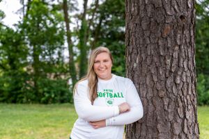 Athletic portrait taken outdoors next to a large tree trunk.