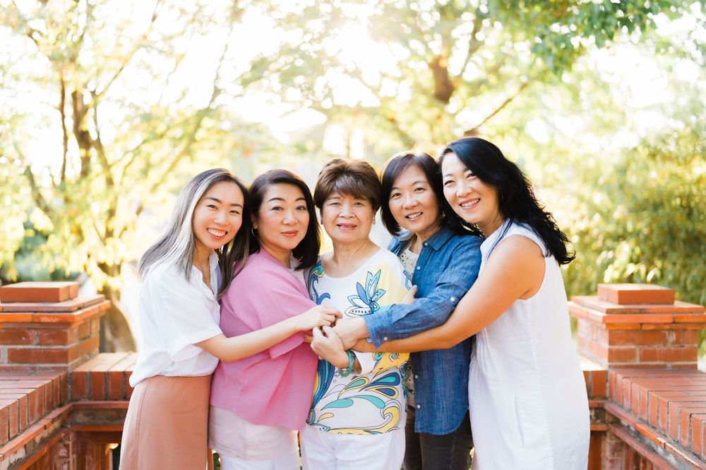 Family group photo outdoors with everyone huddled close together sharing warm smiles.