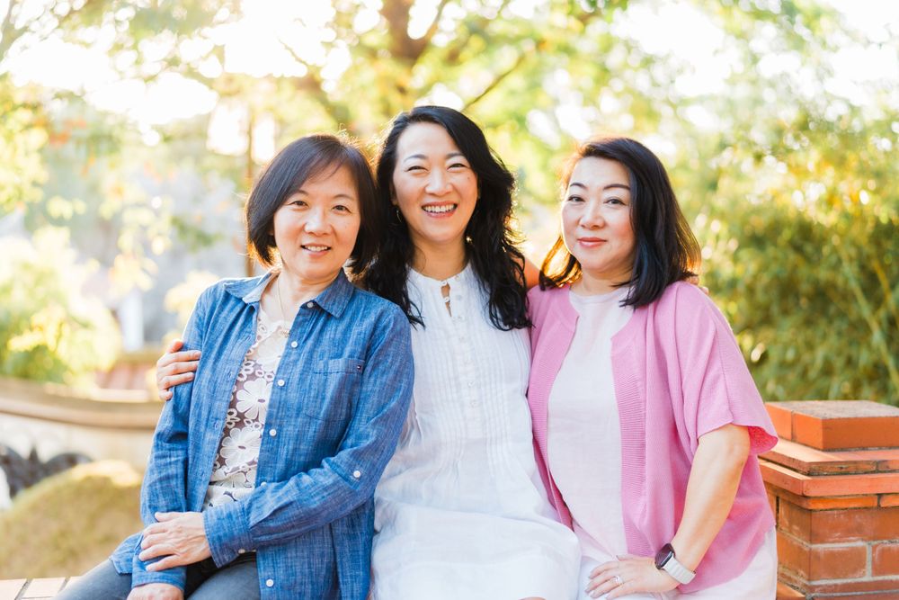 Three friends in casual attire share laughter while posing outdoors.