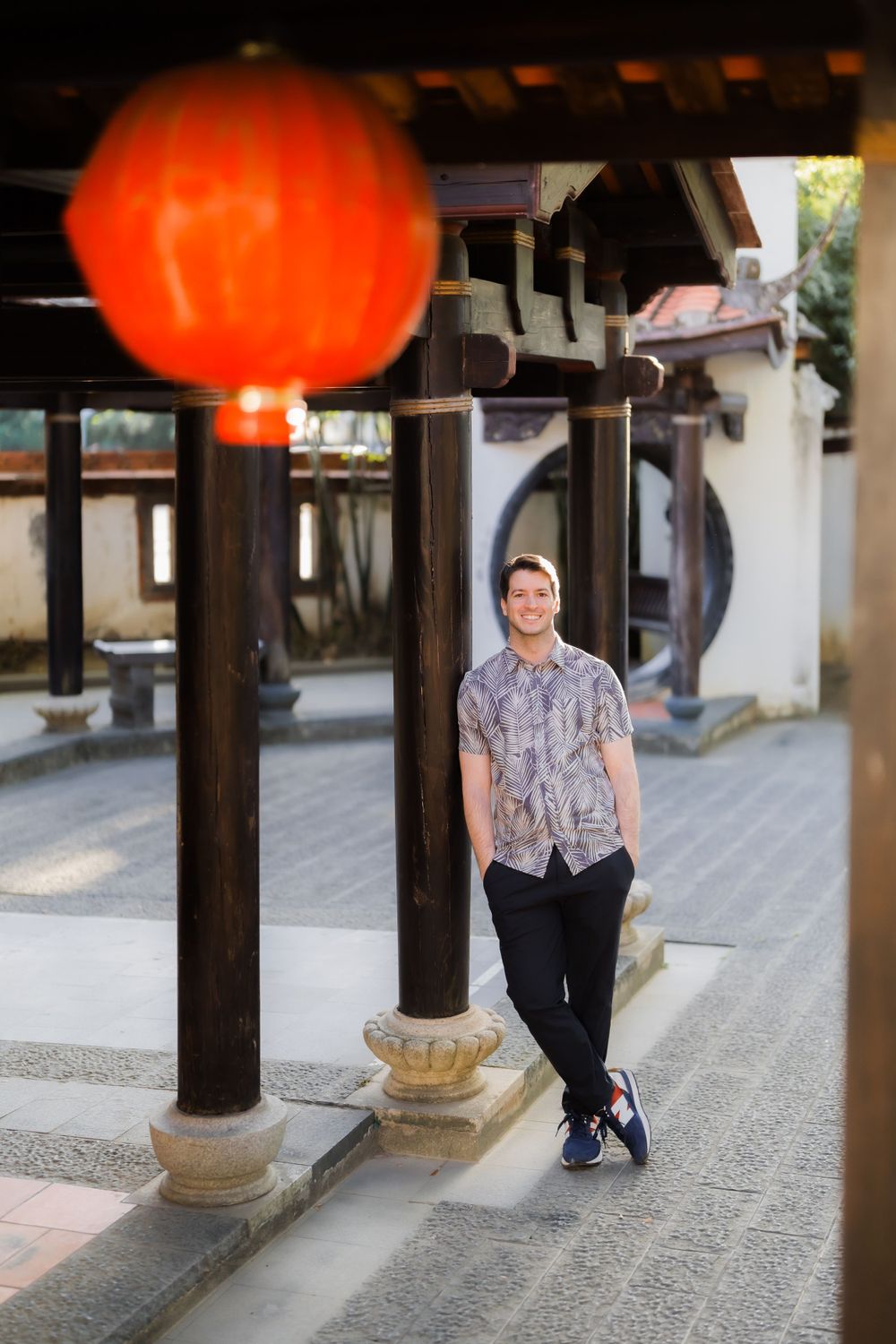 A large red lantern frames an architectural scene with traditional Asian design elements.