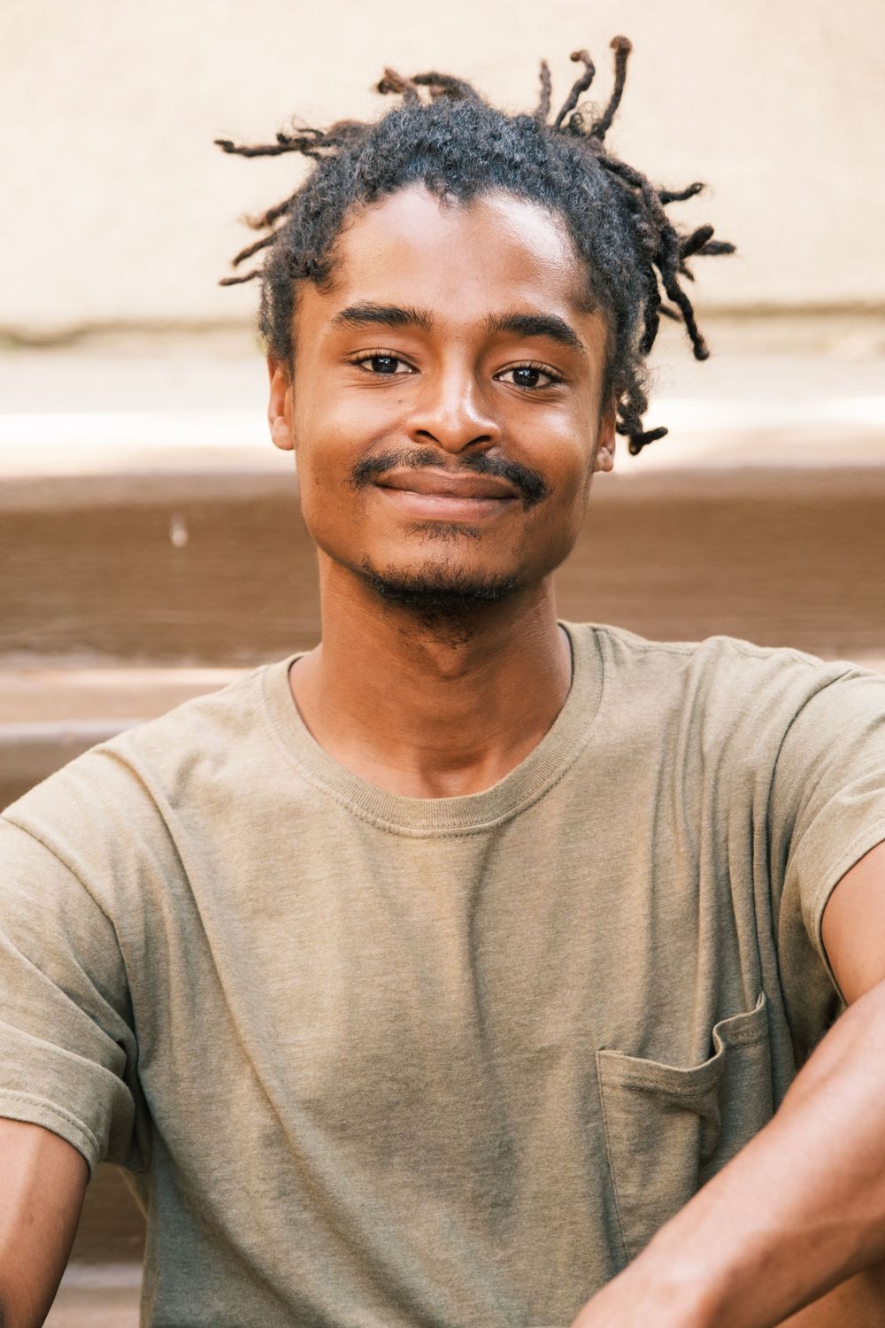 A casual portrait showing a person in a gray t-shirt with styled hair.