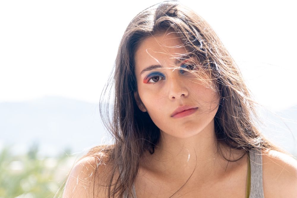 Close-up outdoor portrait with natural lighting and mountain scenery in background.