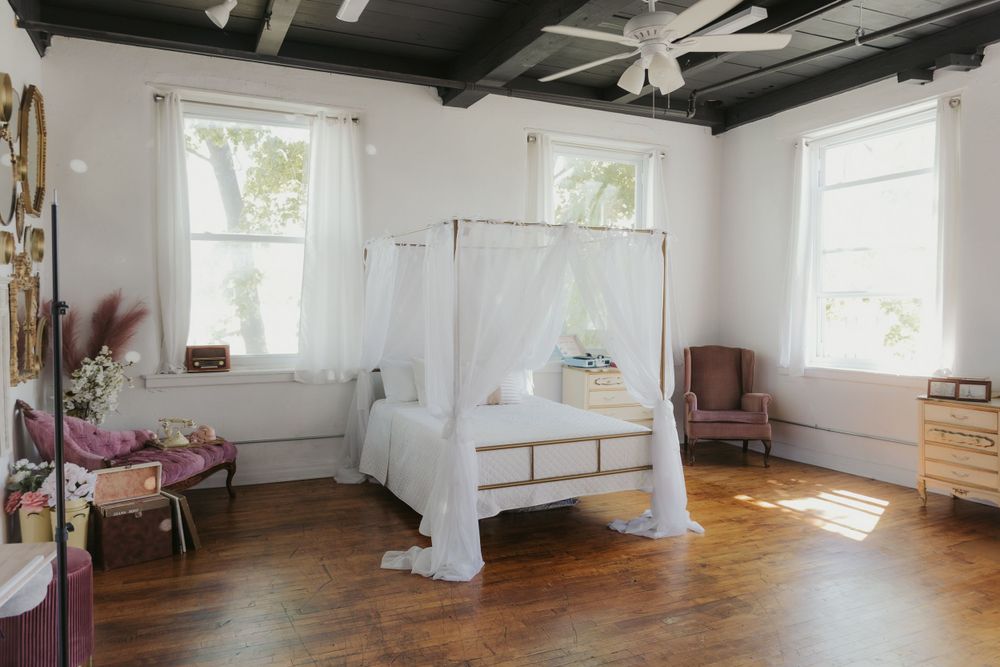 Spacious white photography studio with multiple windows and elegant white drapes.