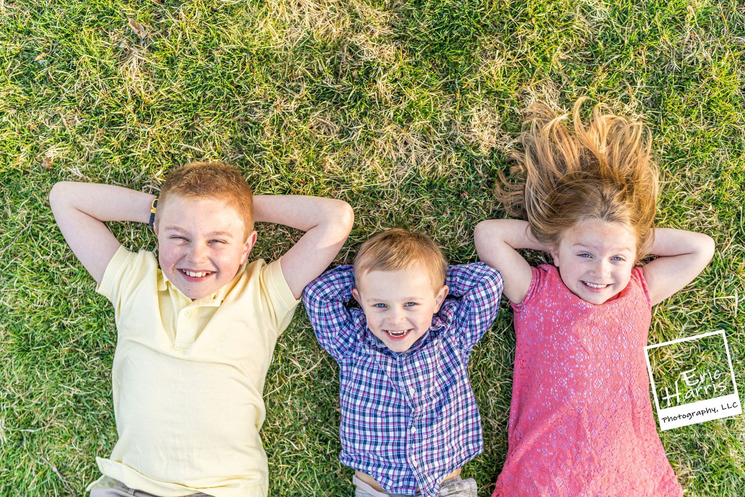 Three kids laying in the grass smiling at Highlands Mansion Fort Washington PA