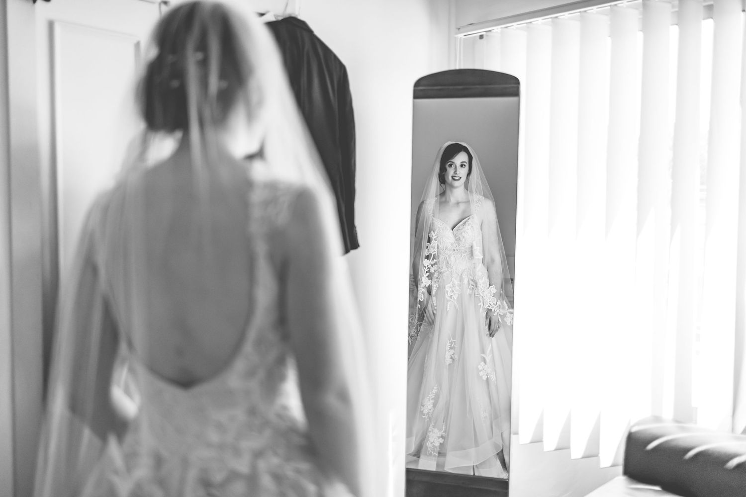 Black and white reflection of bride in white dress preparing for wedding day.