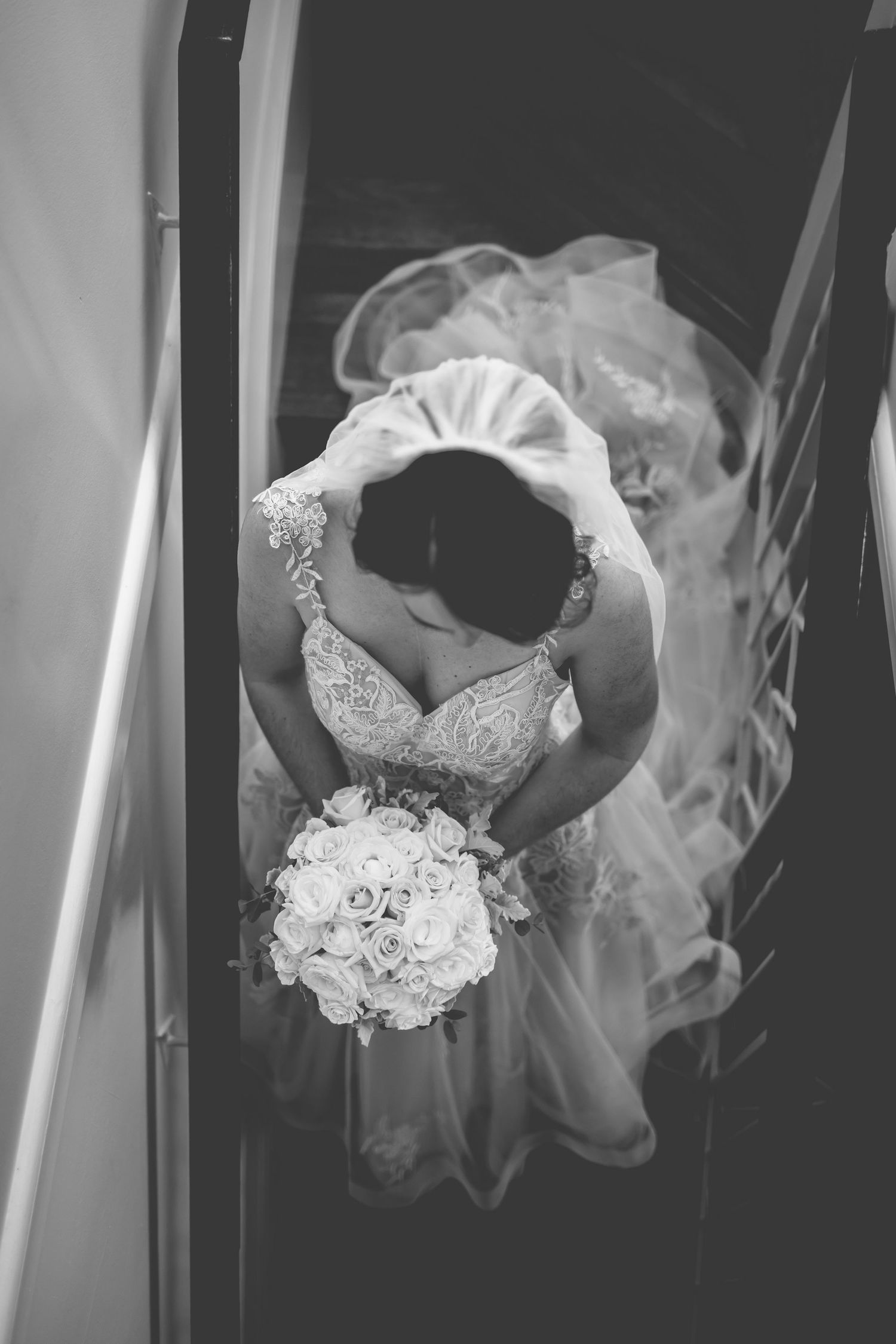 Overhead view of bride in white dress holding bouquet, captured in black and white.