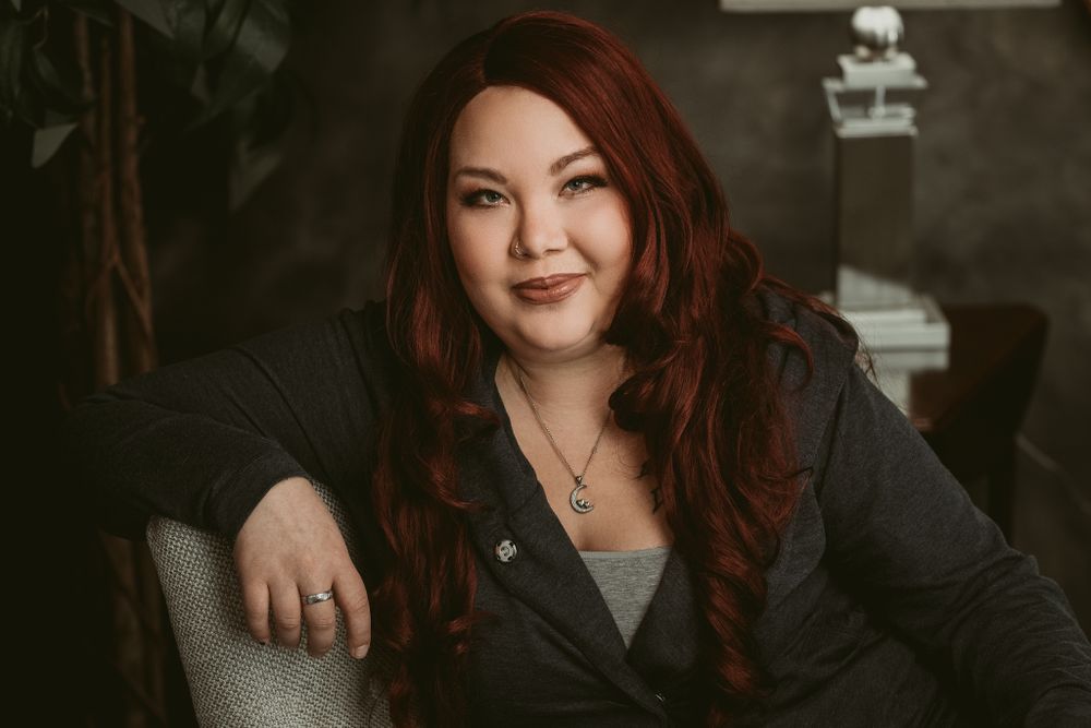 Professional headshot with dark clothing against moody studio backdrop.