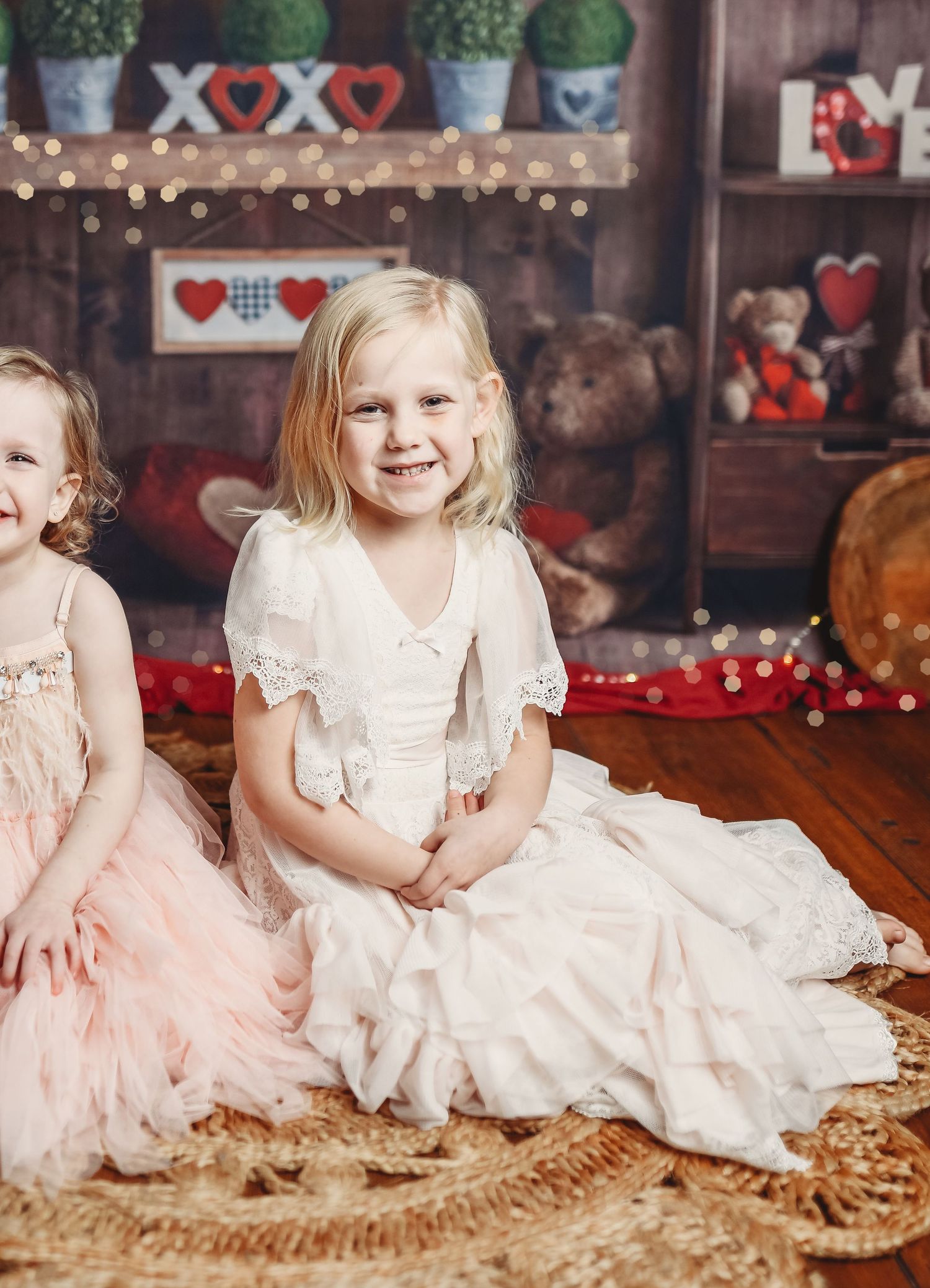 Festive holiday scene with white lace dress amid teddy bears and heart decorations.