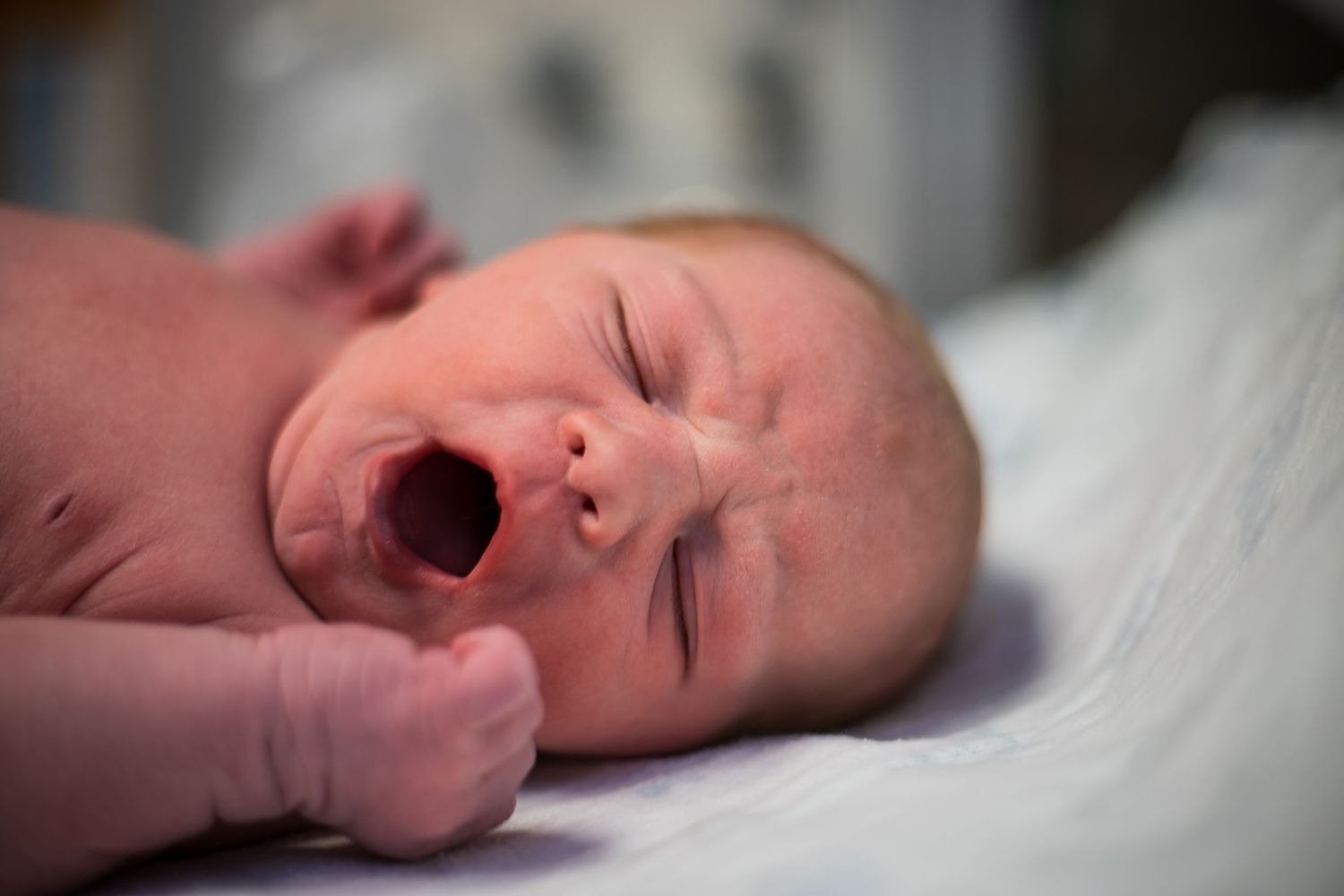 Newborn baby boy yawning just after birth while laying in the hospital warmer in Sioux City, IA.