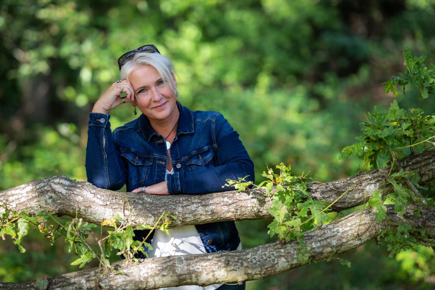 Person resting on a fallen tree trunk in a lush green forest setting.