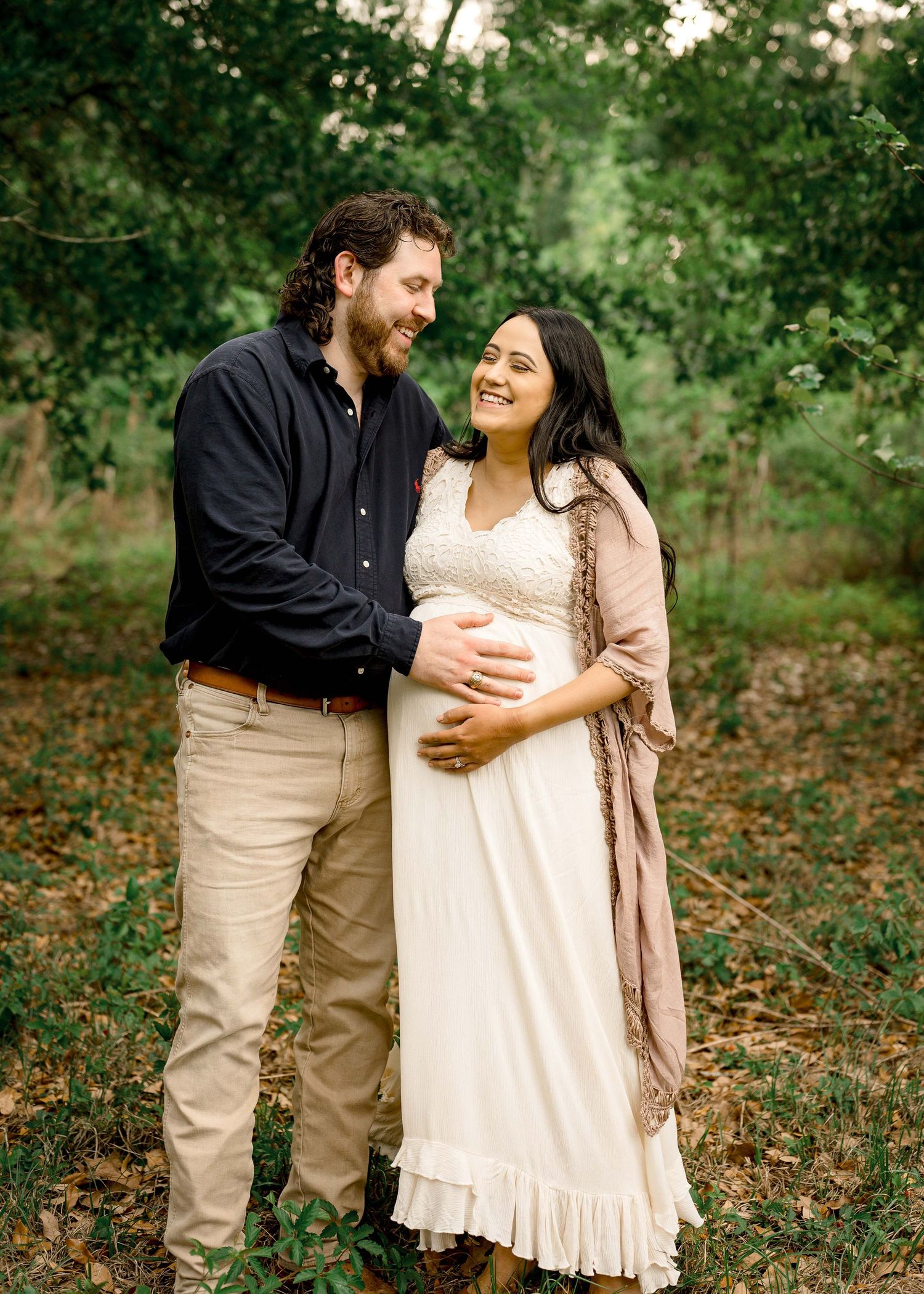 candid moment between husband and pregnant wife taking maternity photos in the forest in houston