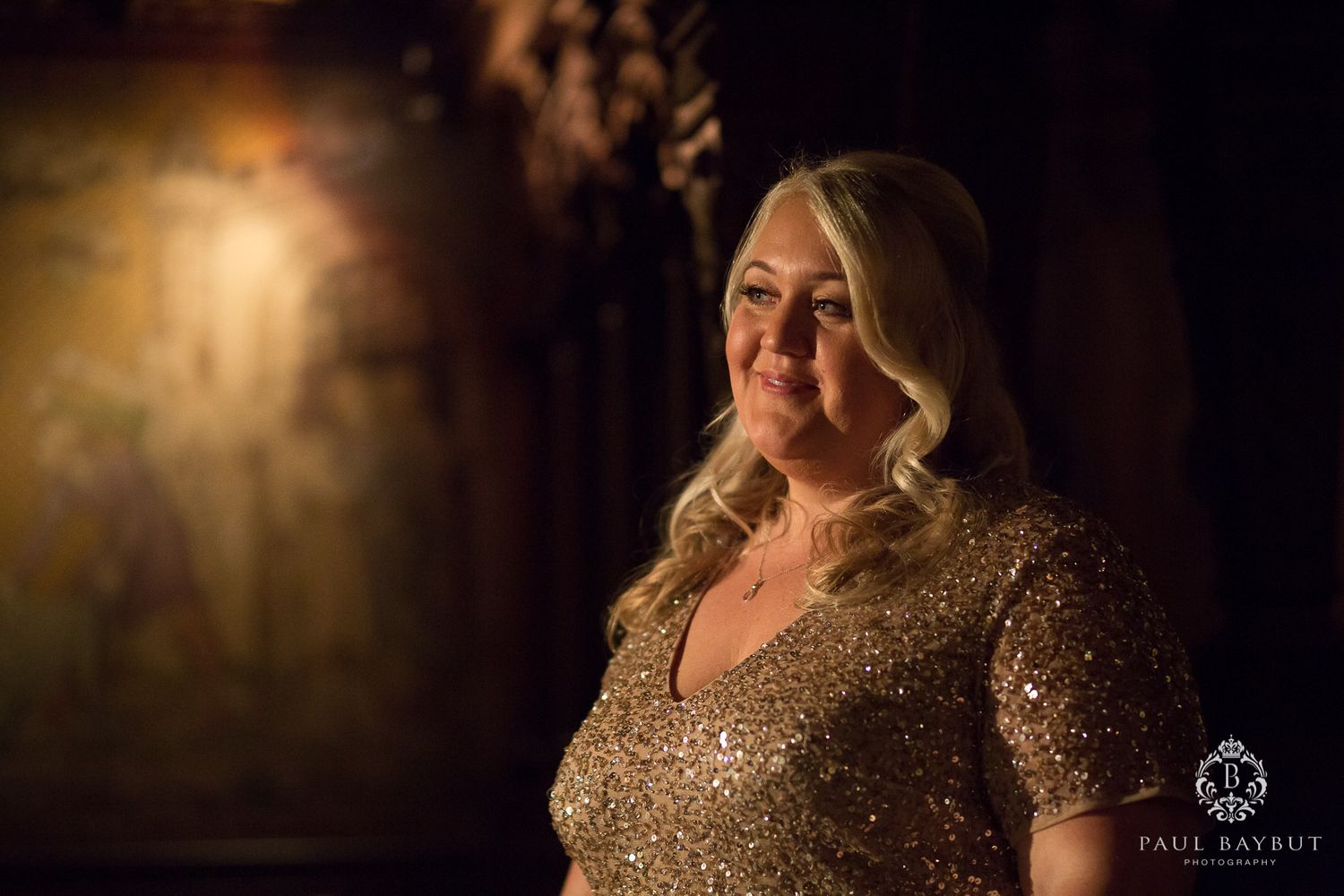 A glowing evening portrait in a sparkly dress against moody lighting.