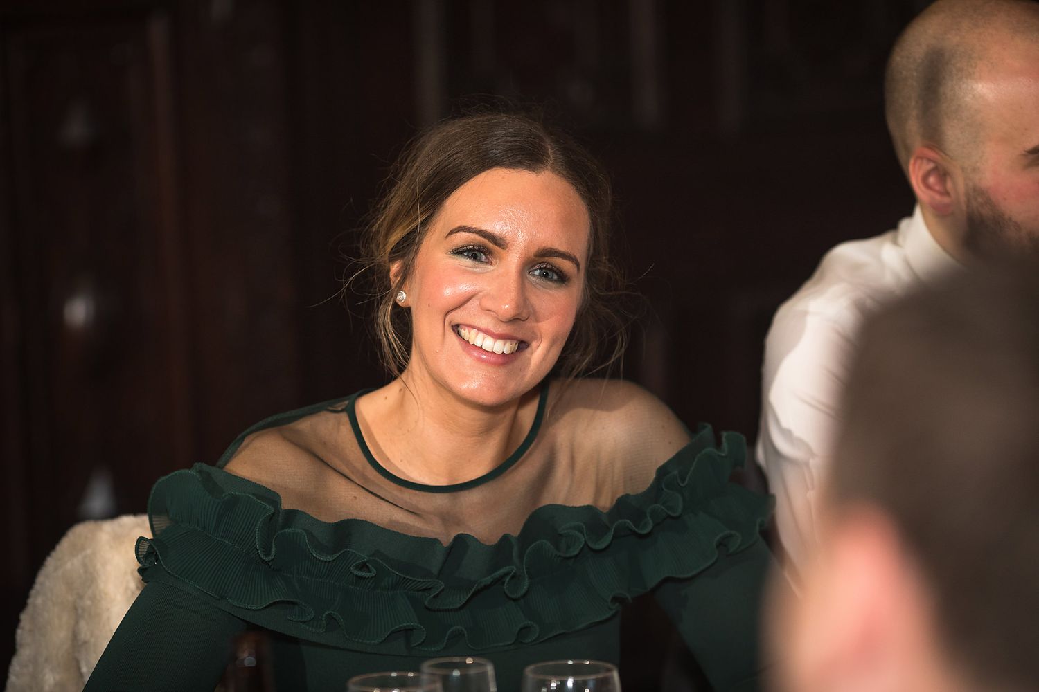 Wedding guest in an emerald green formal dress smiles during reception celebration.