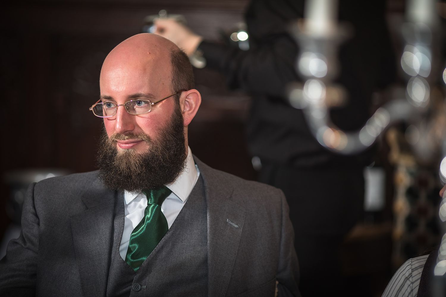 Guest in dark suit and emerald tie poses during wedding reception.