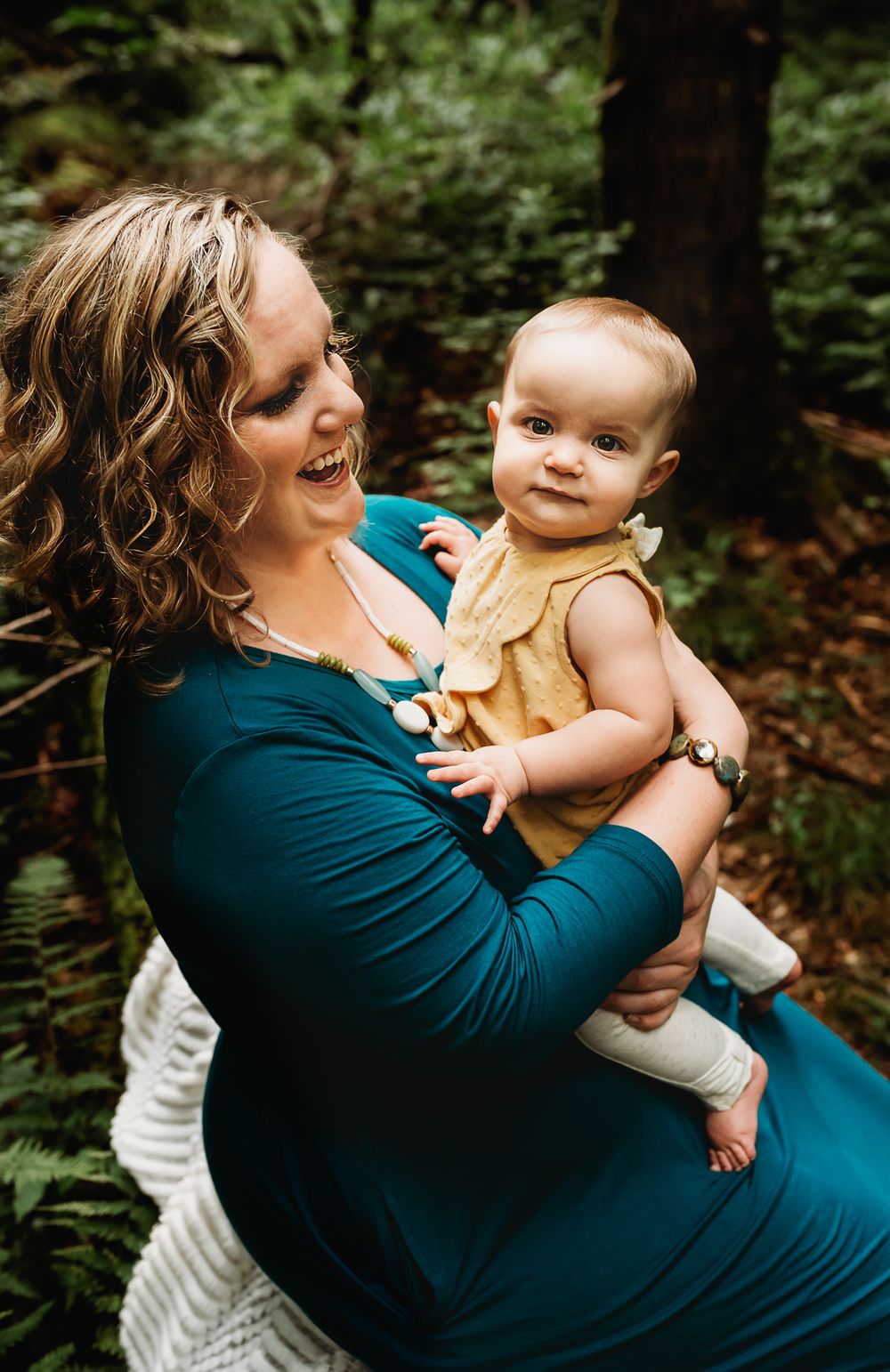 Mother smiling at baby for outdoor photograph in forest
