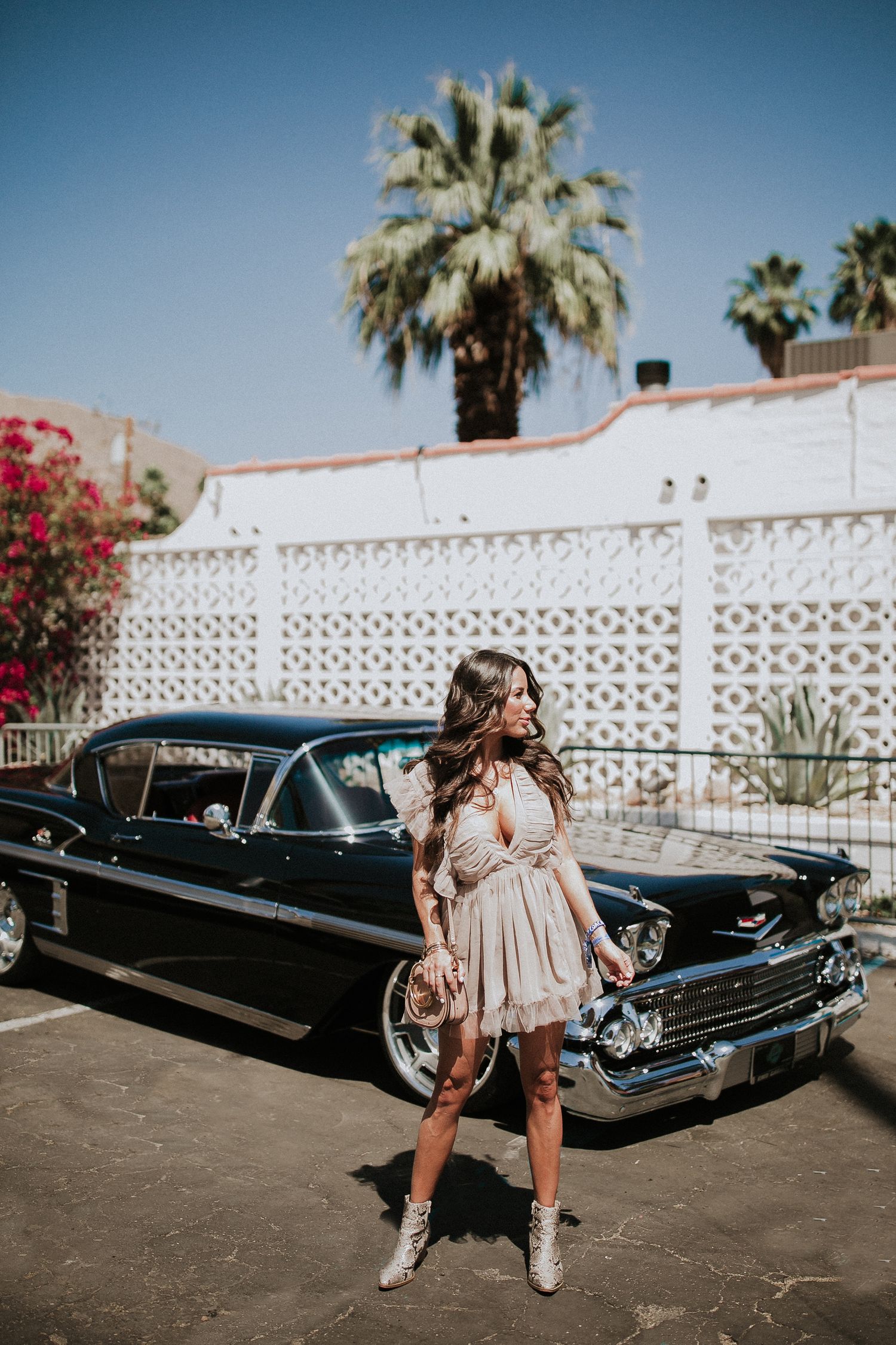 Vintage fashion shoot with classic black Chevrolet and palm trees in desert setting.
