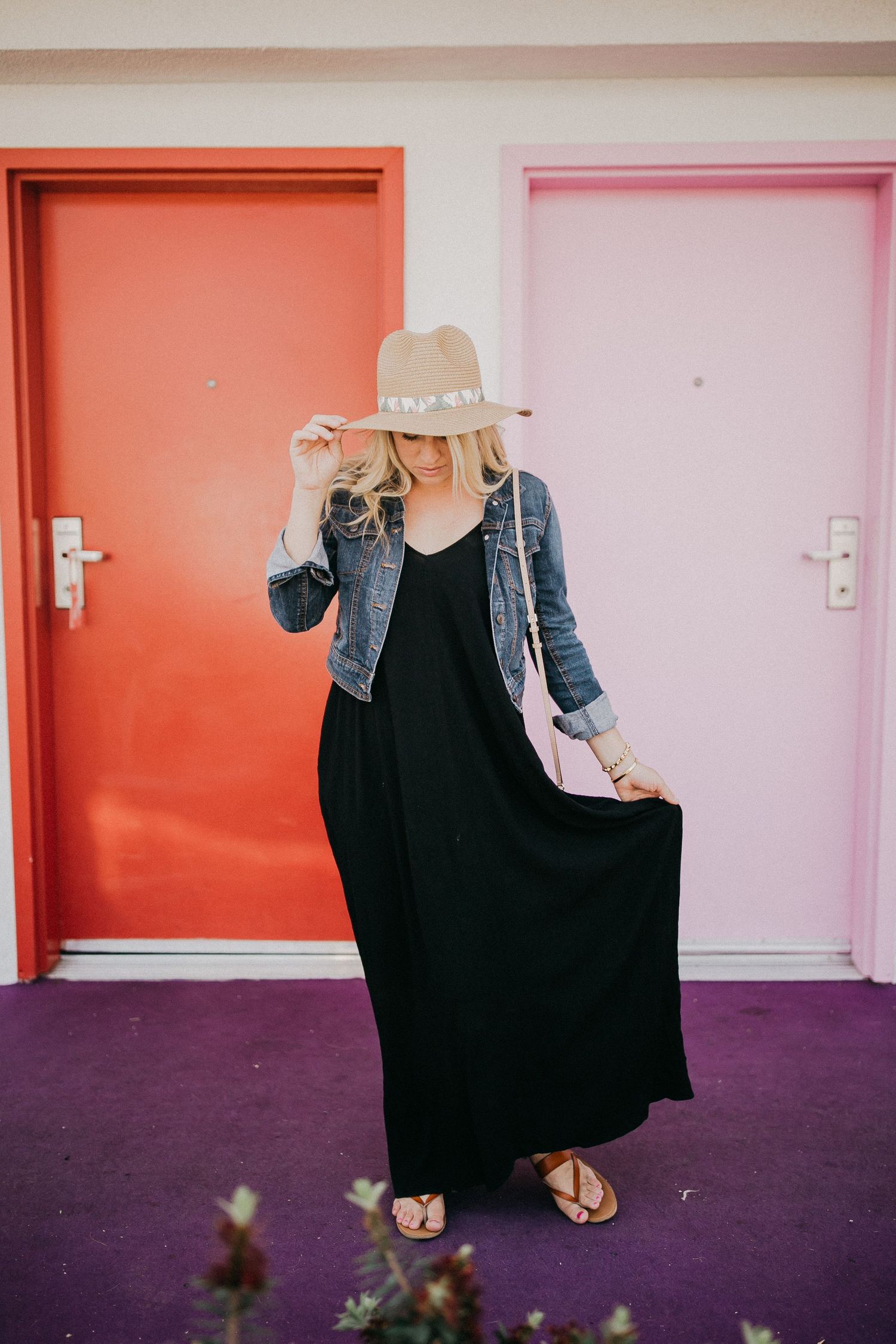 Fashion shot against colorful doors with straw hat and flowing black maxi dress.
