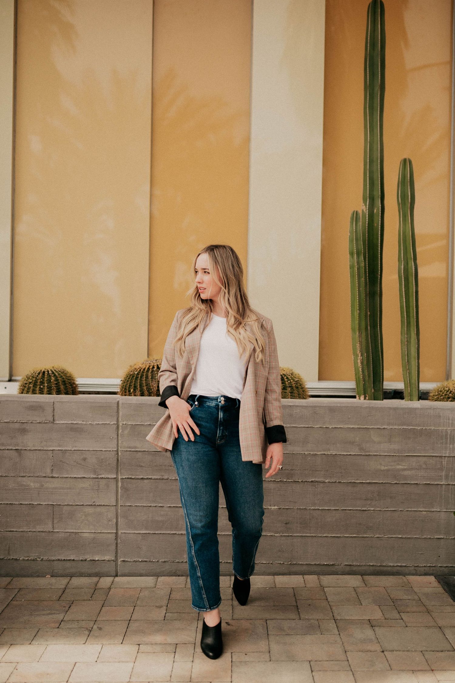 Fashion photo against beige wall with tall desert cacti.