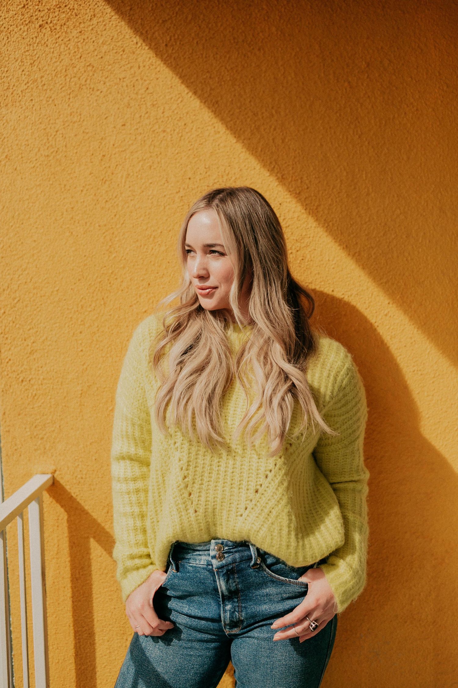 Portrait against orange wall with dramatic diagonal shadow.