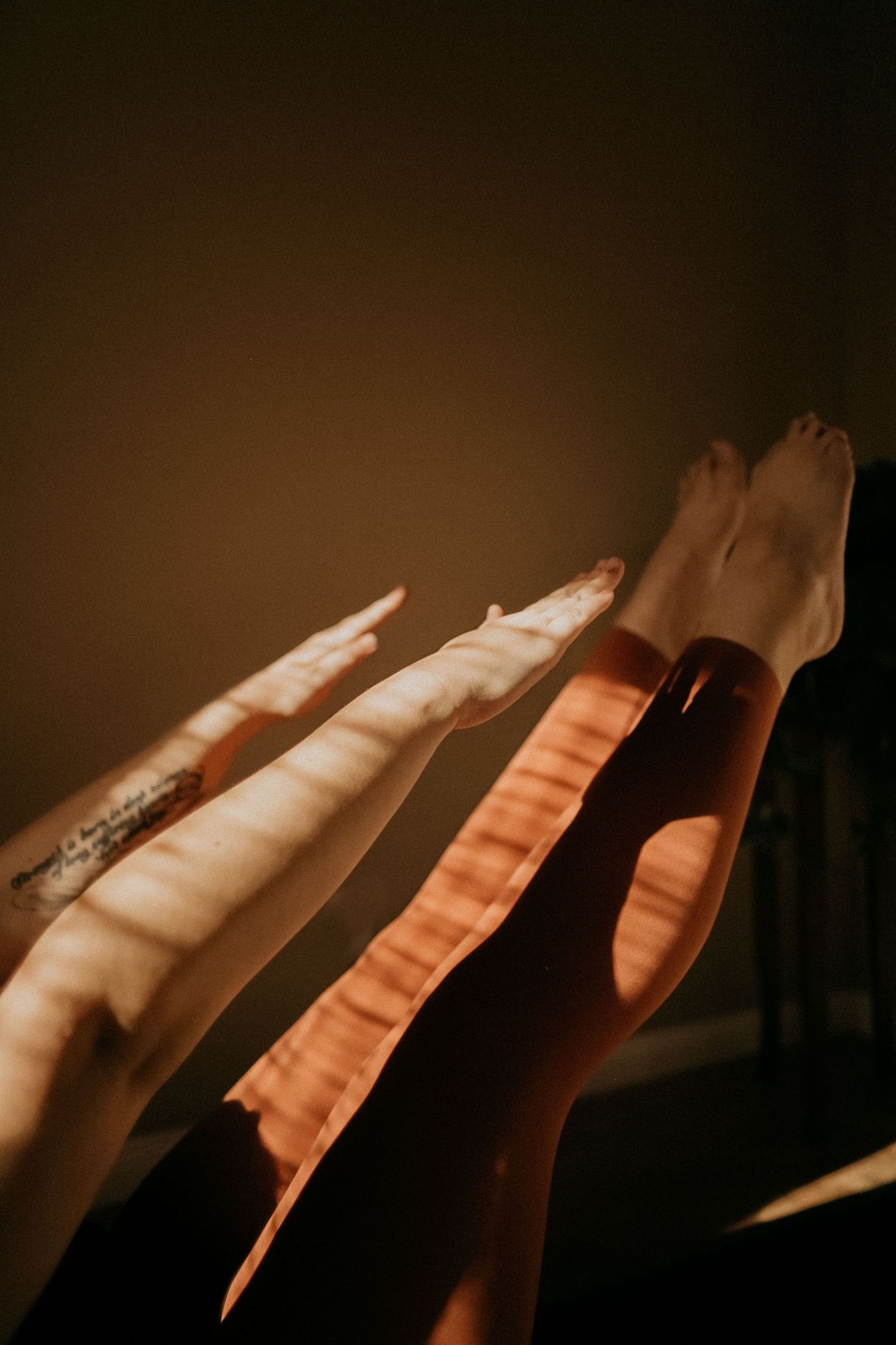 Artistic photo of legs with striped light patterns in moody brown tones.