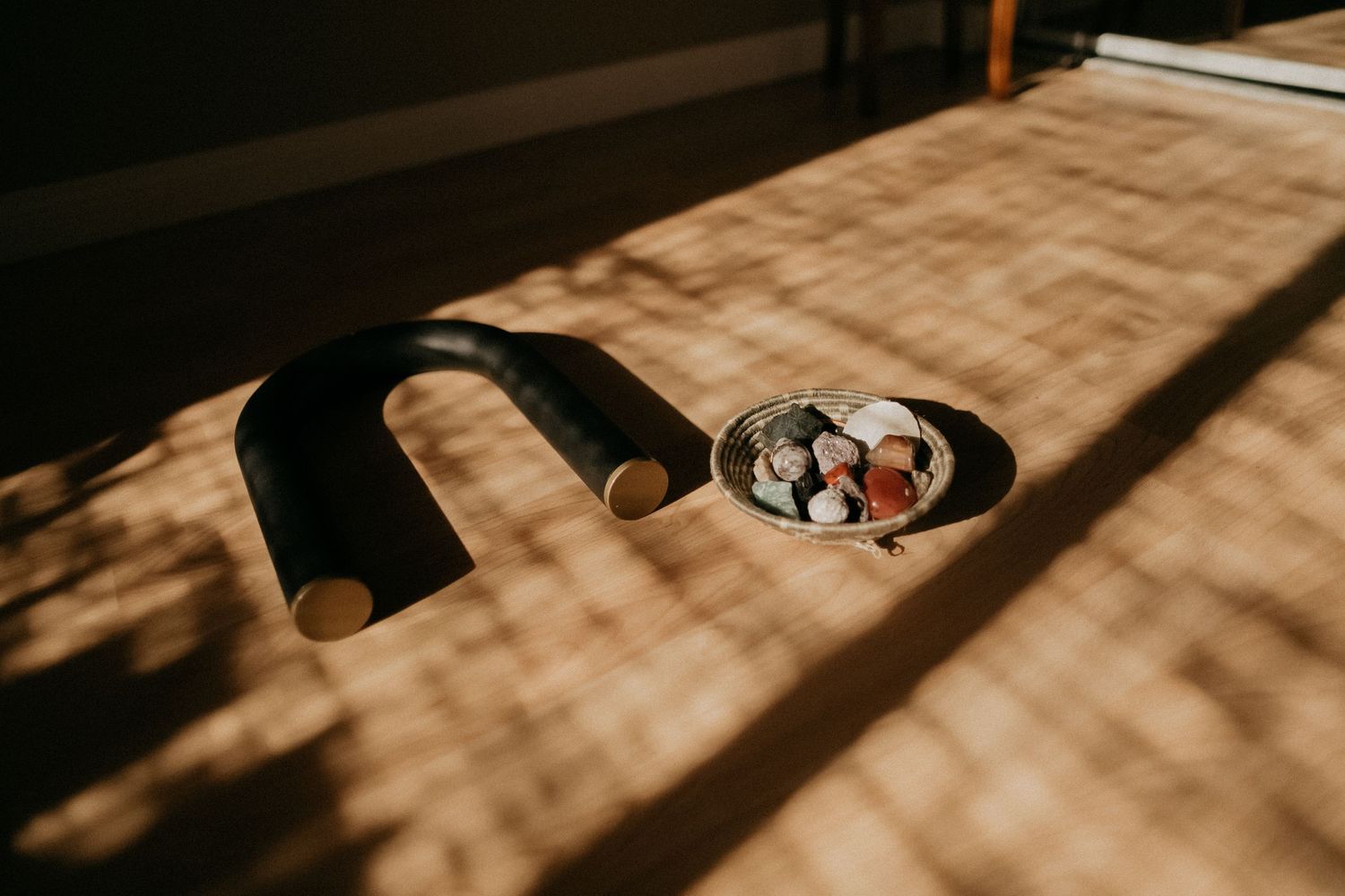 Sunlight streaming across wooden surface with headphones and small dish in frame.