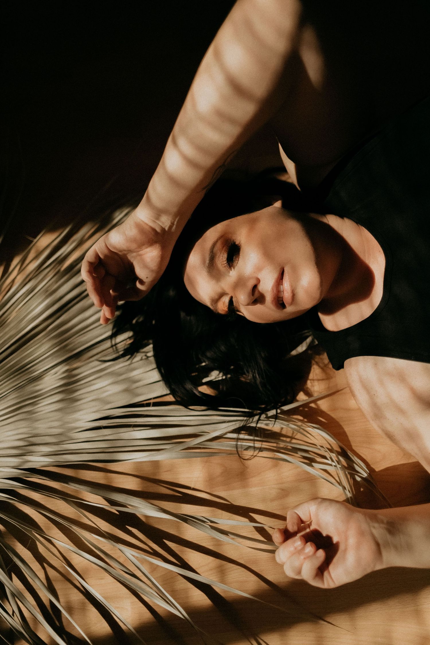 Artistic portrait with palm frond shadows creating a dramatic lighting effect.