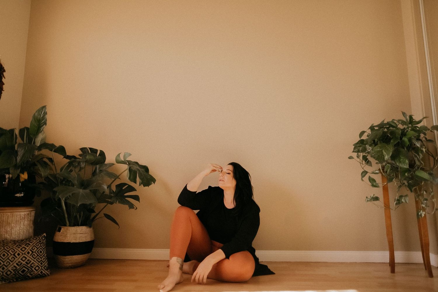 Indoor scene with potted plants and person sitting against beige wall.
